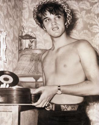 Elvis Presley, hatted and shirtless, holds a stack of 45’s of “That’s All Right, Mama,” his first commercial recording. Bettmann / Bettmann Archive styles medium public images blog posts Adam Dupuis 2016 11 22 sub buzz 13403 1479837288 1